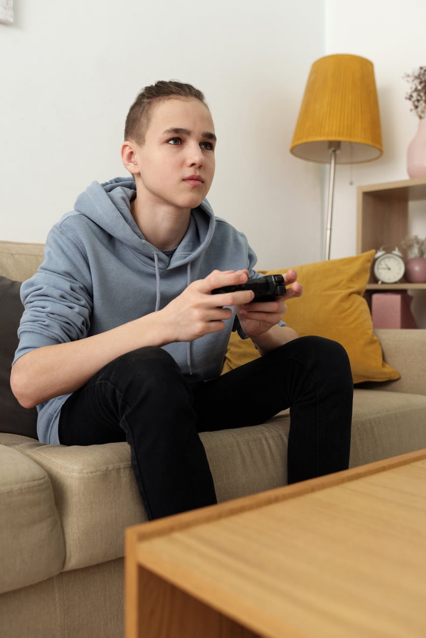 boy in gray hoodie and black pants sitting on couch